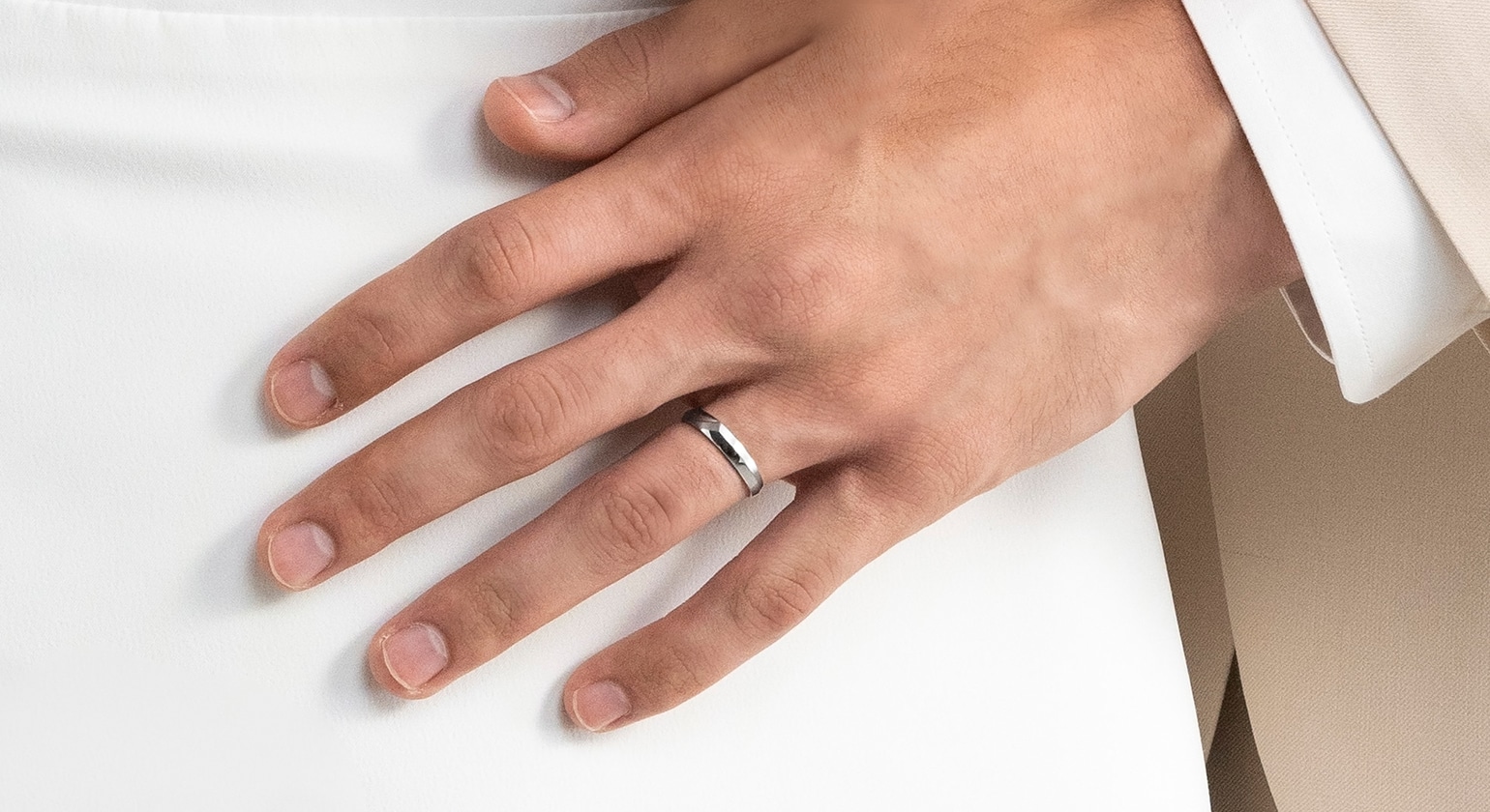 A male hand wearing a wedding band